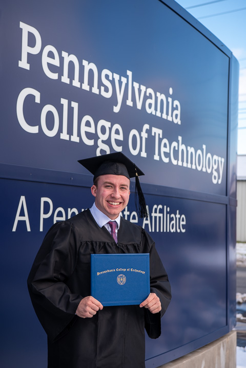 Nicholas M. Snow, a plastics & polymer engineering technology and Wildcat cross-country runner, punctuates his Penn College successes with a stop by the entrance sign. 