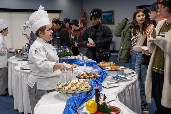 McKenna J. Morgan talks visitors through her selections, which included an apple tart; mini eggnog cheesecakes; almond, cranberry and orange biscotti; everything bagels with garlic Parmesan spread; and coffee bonbons.