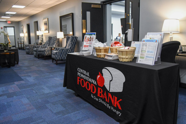 An information table for the sponsoring Central Pennsylvania Food Bank welcomes PDC guests. The local nonprofit provided a dinner prior to the simulation, and hosted two food-packing events during Dream Week as service opportunities for members of the Penn College community.