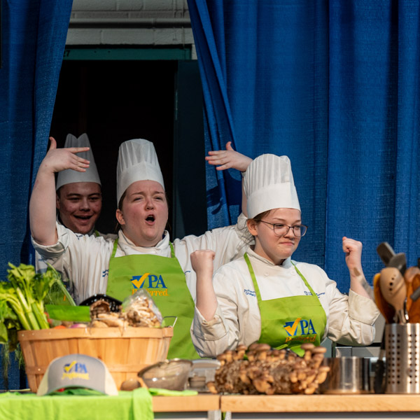 Students make a spirited entry to the stage to face the School Cooking Challenge. The students divided into two teams to conquer a grocery bag of surprise Pennsylvania ingredients that they quickly transformed into tasty dishes for a panel of judges.