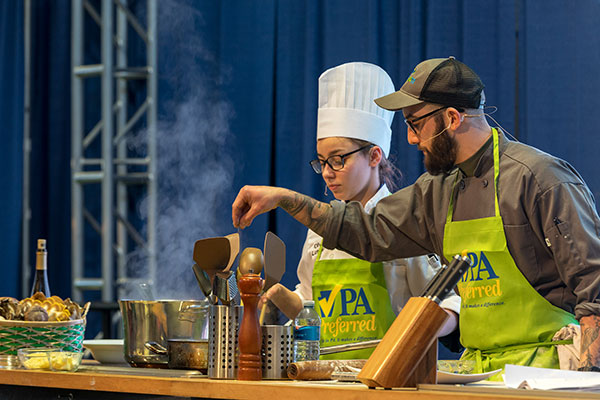 Darren J. Layre, a 2015 Pennsylvania College of Technology alumnus in culinary arts & systems and culinary arts technology, works with 2018 baking & pastry arts graduate Olivia M. Lunger at the 2019 Pennsylvania Farm Show. Layre will be among the successful alumni returning to the Farm Show stage in Harrisburg this month for the state’s 107th annual agricultural exposition. (Photo by Davey Rudy, PA Preferred)
