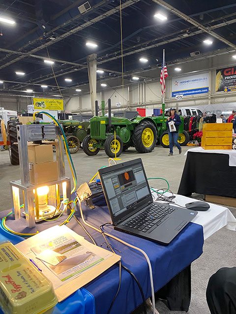 The green and yellow colors of John Deere equipment, displayed opposite the college booth, are recognizable reminders that this IS an agricultural expo! 