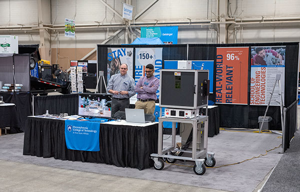 A knowledgeable duo takes a turn at the college's Farm Show booth: Howard W. Troup (left), assistant professor of automated manufacturing/machine tool technology, and Krishna C. Vistarakula, instructor of manufacturing engineering technology. The pair was assisted by Paul W. Albright, another faculty member in manufacturing engineering technology.