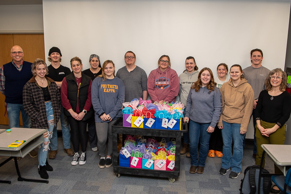 With 62 gift bags ready to roll to the Children’s Learning Center, the PTK members who pitched in pause for a memory-making moment with advisers John F. Tamblin (far left), assistant professor of chemistry, and Karen L. Avery (far right), assistant professor of biology.
