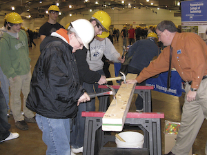 Steven K. McCoy, coordinator of matriculation and retention for the School of Construction and Design Technologies, directs participants in a nail-driving contest.
