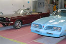 A 1965 Ford Mustang and a 1978 Pontiac Firebird Esprit, both restored to museum quality by Penn College students, are displayed in a paint bay