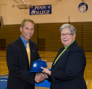 Scott Kennell, Pennsylvania College of Technology's new director of athletics, accepts congratulations - and a Wildcats cap - from President Davie Jane Gilmour on Wednesday.