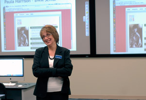 With side-by-side screens as a backdrop, Denise S. Leete, associate professor of computer science, greets visitors to an open house in the Web and Interactive Media Lab.