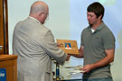 Wrestler Ethan Boyd is presented with a plaque upon the sport's return to Penn College