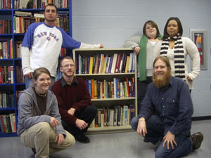 CACCE members and their adviser display a newly installed bookshelf with educational materials (donated by Pennsylvania College of Technology faculty, staff and students) to the Tioga County Prison. Back row, from left, are students Brandon J. Close, of Williamsport, business management%3B Jamie L. Haight, of Sunbury, technology management%3B and Ariel B. Helton, of Williamsport, individual studies. Front row, from left, are student Amber L. Eck, of Williamsport, pre-applied health studies%3A surgical technology%3B adviser Jeremiah C. Gee%3B and student John D. Nicholson, of Lewisburg, studio arts.