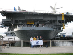 Four members of Penn College's Construction Management Association are dwarfed by the USS Midway aircraft carrier during their visit to San Diego.