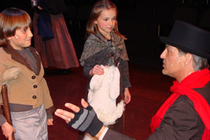 Bob Cratchit, portrayed by Pennsylvania College of Technology faculty member Jeff J. Vetock, sings to his 'Christmas Children%3A' Tiny Tim (Levi Roush) and Kathy (Jordan Kelley).
