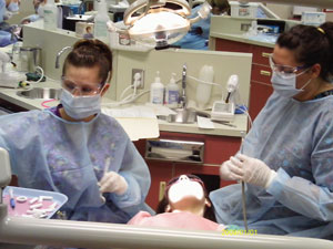 Pennsylvania College of Technology students Michelle J. Chea, of Dauphin, left, and Maria J. Mielnik, of Hollidaysburg, provide preventive dental services to a  child.