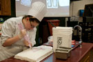 Ariel Woodring writes a birthday greeting for one of the visiting third-graders onto a sheet cake