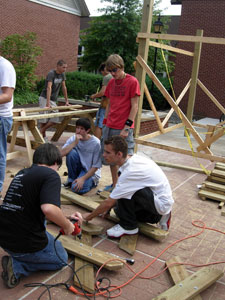 Devin Croyle, Robert Duda, Andrew Bomberger and Andrew Hoover work as a team to bring pieces of the table together.