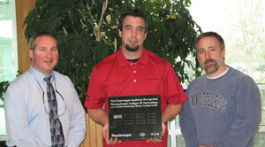 Shane Conner, product trainer for the Eaton Corp.%E2%80%99s regional territory, holds a plaque certifying Pennsylvania College of Technology as a factory-authorized training facility, joined by Brett A. Reasner, assistant dean of natural resources management (left), and Mark E. Sones, instructor of diesel equipment technology.