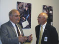 Vincent J. Matteo, Chamber president and chief executive officer (left), talks with Steven P. Johnson, president/CEO of Susquehanna Health, under photos that depict Penn College's 'degrees that work'