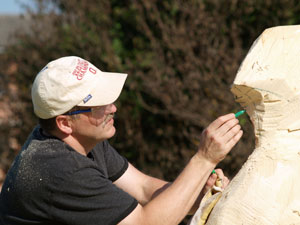 Brian A. Flynn, assistant professor of graphic design, marks out a plan as he transforms a spruce log to a 7-foot sculpture during the 17th Estonian Wood Carving Symposium.