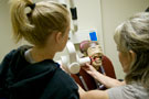 With the assistance of a dental hygiene faculty member, a camper prepares to X-ray a 'patient'