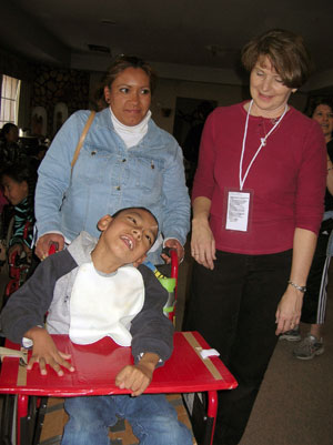 Patricia J. Martin, right, clinical director for Pennsylvania College of Technology%E2%80%99s occupational therapy assistant program, with a client whose wheelchair did not fit him, so using pool noodles, duct tape and cardboard, the visiting therapists created a seat, back and foot rest to help position him better in the chair, as well as a lap tray to improve positioning of his upper extremities and provide a surface to use his hands for functional activities. 