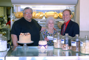 Robert C. Dietrich, right, executive director of the Penn College Foundation, accepts a scholarship check from Francis Daniele and his mother, Joanna, behind the counter of Joanna%E2%80%99s Italian Bakery, 445 Market St.