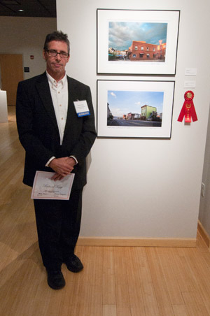 Rick Karp, %E2%80%9982, of Williamsport, with his second-place photo entry %E2%80%9CShoe Repair Shop, Market Street,%E2%80%9D at the opening reception for 'Kaleidoscope%3A The Alumni Exhibit' at The Gallery at Penn College. (Photo by Michael R. Fischer, student photographer)