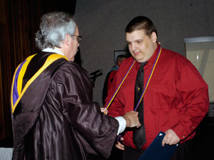 Tom Gregory, associate vice president for instruction, presents Andrew N. Kroft with his Delta Mu Delta honor cord.
