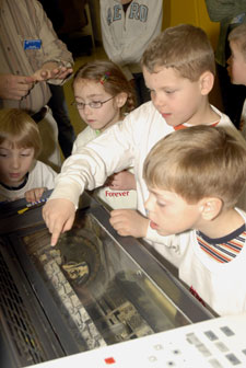 First-graders watch with interest as thousands of sheets of paper are printed with college letterhead.