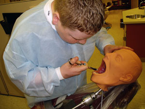 A NEO Guy injects solution into a dental hygiene manikin.