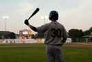 An on-deck batter spends his moment in the dwindling sun