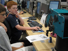 Students program a tabletop robot in one of Penn College%E2%80%99s electronics and computer engineering technologies laboratories.