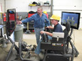 Eric J. Buckley operates a Caterpillar simulator, under the helpful eye of instructor Budd Greevy
