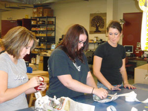Members of the Community and Organizational Change class at Penn College, from left, Bridget Hockenbroch, Maranda Kromer and Nicole Gross, pack merchandise during a field trip by the class to volunteer at a Ten Thousand Villages warehouse in Akron.