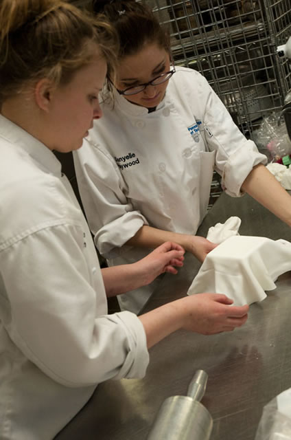 Students add fondant to a contest cake during their last work session before the contest.