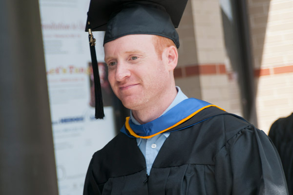 A grad offers a smile during the procession.