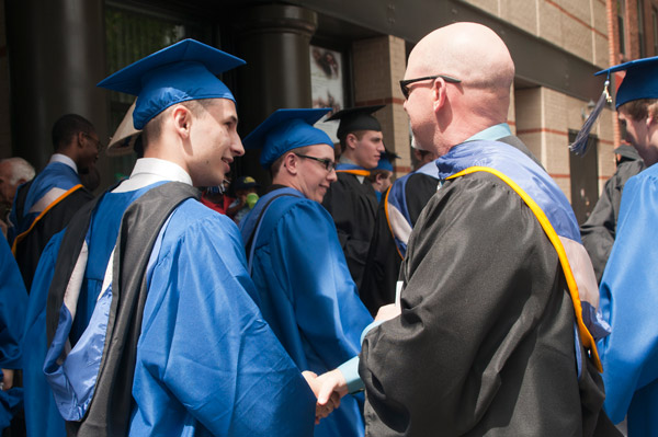 Walter V. Gower, assistant professor of aviation, shakes hands with graduates as they leave the Community Arts Center. 