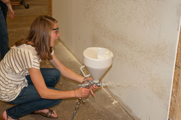 A student from Mansfield Jr./Sr. High School uses a texture gun to apply knock-down finish to drywall.