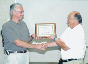 Ransome CAT's Ronald Garber accepts a 10-year plaque from Wayne R. Longbrake, dean of natural resources management.