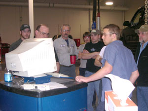 Jim Wrigley, a senior trainer for Chief Automotive Systems (behind monitor) instructs a group that includes students Brandon Smith (foreground) and Nathan Chilson (center, in black T-shirt).