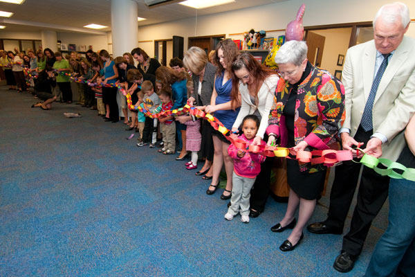 President Gilmour and Chairman Dunham participate in the Children's Learning Center ribbon-cutting with children, parents, staff, faculty and students. The paper-chain ribbon was created by the centers children. 