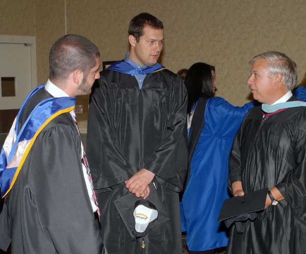 Colin W. Williamson, dean of transportation technology (right), shares a word or two with graduating students.