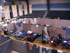Sleeping accommodations comprise cots on gymnasium floor.