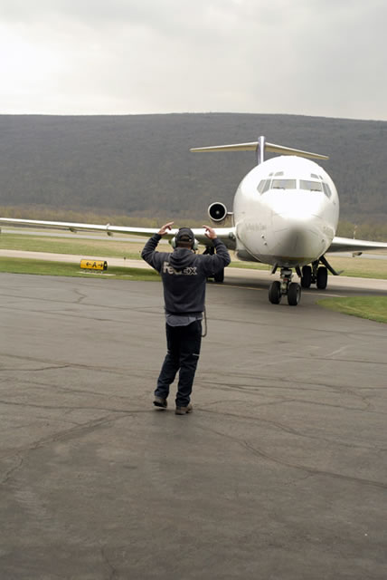 A FedEx crew member guides the plane as it taxis closer to its new home.