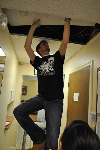 Brandon S. Haney replaces a water-damaged ceiling tile.