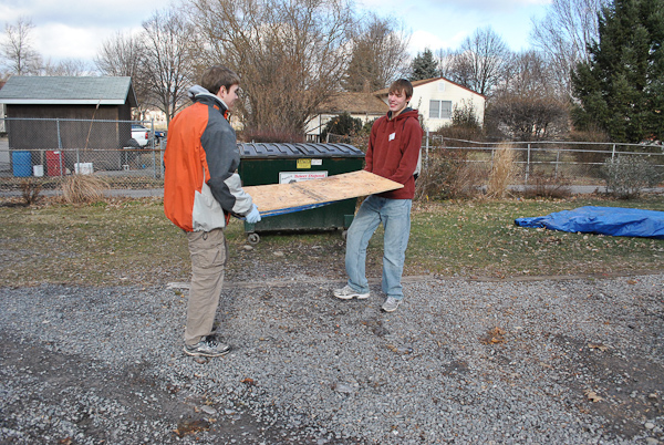 Adam C. Swan and R. Quinn Ross move plywood out of the wintry weather.