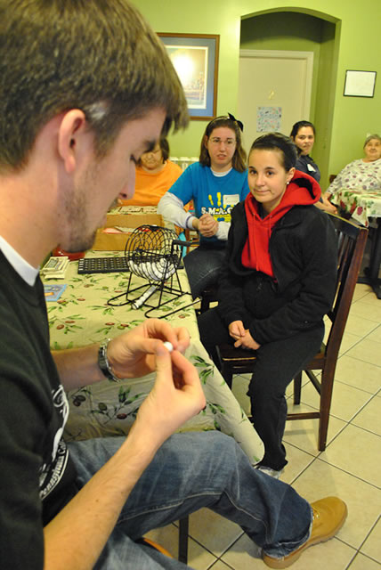 Brandon S. Haney calls out numbers, while other students help residents play bingo.
