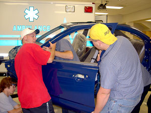 Ryan C. Chilson, Bradley A. Larson, Fred A. Schneider III, and Eric S. Chilson reinstall the driver's door Friday morning in the Paramedic Lab. (Photo by Stephen T. Duna, instructor of collision repair)
