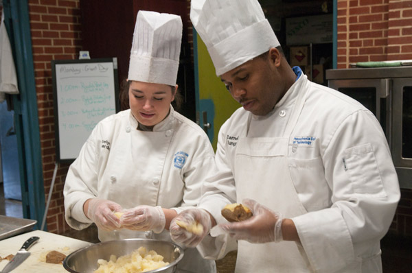 Katelyn R. Ciavardini and Darnell R. Bungy, both seniors in the culinary arts and systems major, prepare potatoes for a baked potato soup demonstration by Kathy Wickert, chef at Giant Super Food Store Cooking School.