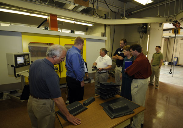 Gary E. McQuay, PMC project manager (in white shirt at center), explains operation of a CNC trimming machine on loan to the college from Geiss Thermoforming USA. 