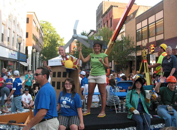 Students Erica Schreffler, in solar house and carrying a wind turbine, and Ashley Beatty add a touch of "green" to the college float, representing the School of Construction and Design Technologies' building science and sustainable design major.